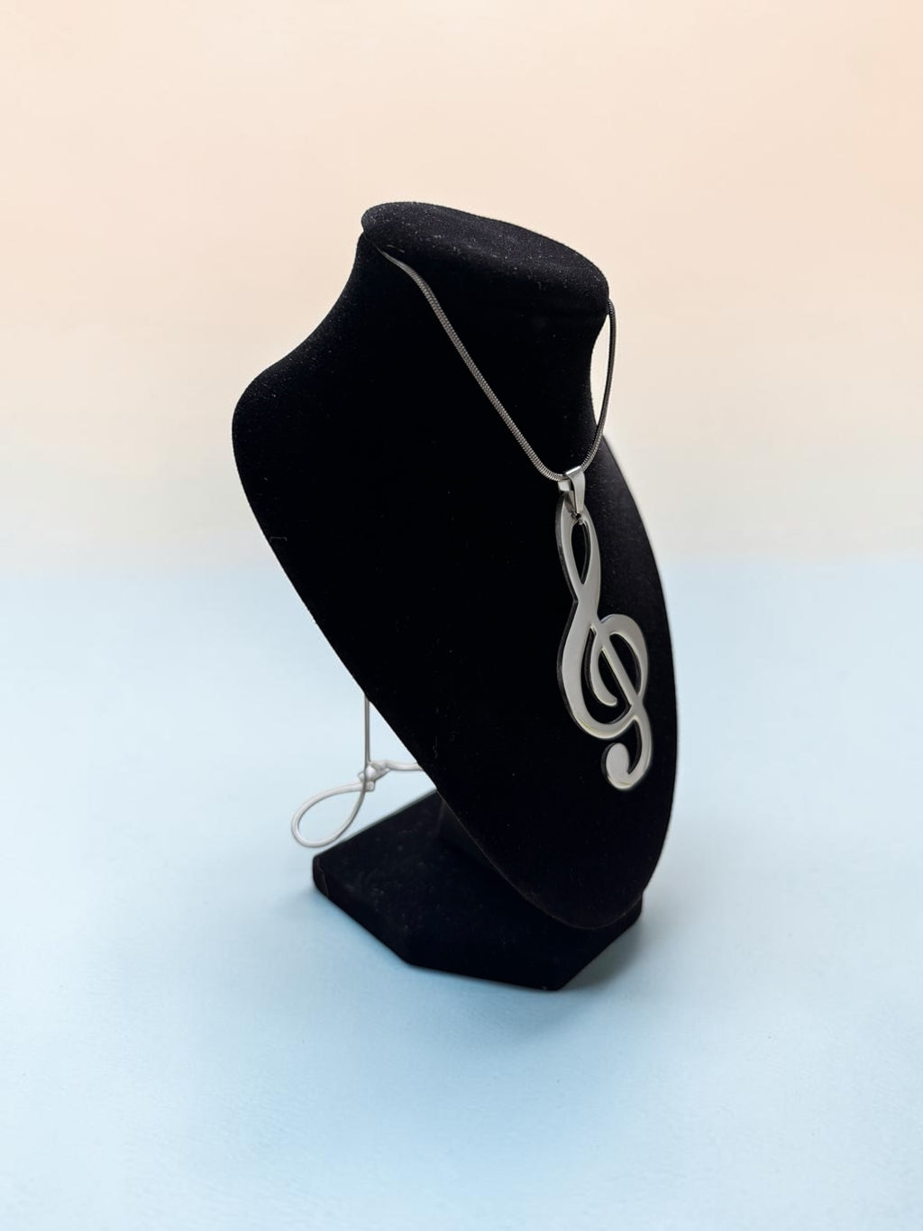 Smitsjewellery zilverkleurige vioolsleutel hanger aan een subtiele ketting op een zwarte display buste.